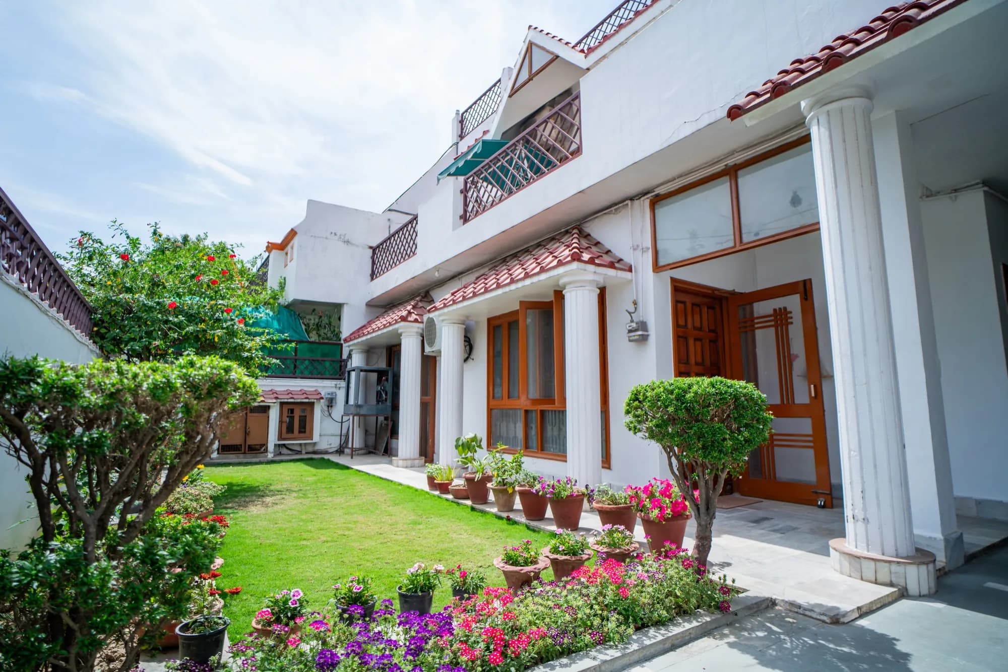 The garden side of Matrika HomeStay, with the veranda and potted plants